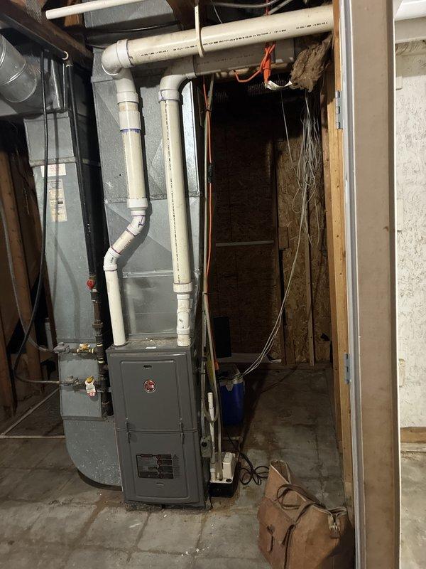 Conducted comprehensive assessment of 20-year-old furnace and generator system located in basement mechanical room. Current equipment operational but nearing end of service life. Evaluated existing gray HVAC furnace with complex PVC venting system, including multiple vertical risers and horizontal runs with elbow joints for proper combustion air and condensate drainage. Inspected refrigerant lines, electrical connections, and ductwork configuration. Documented equipment specifications, clearances, and existing infrastructure including water heater proximity, exposed framing, and available space for new installations. Provided replacement estimate for modernized high-efficiency furnace and generator system to improve reliability, energy efficiency, and performance.