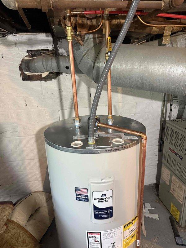 Installed Bradford White tanked water heater model RE350S61NCWW in residential basement utility room. Connected copper supply lines and discharge piping to existing plumbing infrastructure, positioned unit on drain pan per code requirements, and verified all connections for proper operation. Mechanical permit was obtained prior to installation for hot water tank reconnection work.