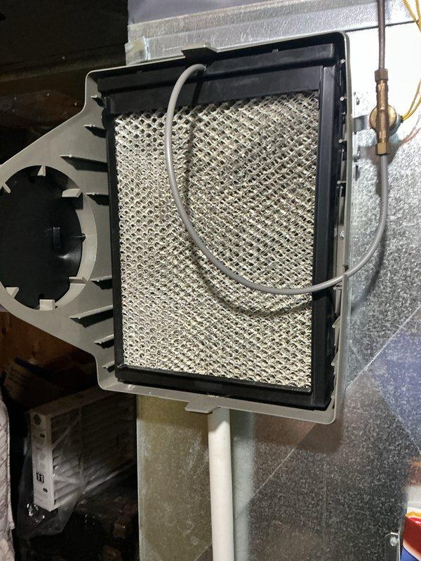 Completed annual cooling maintenance on residential HVAC system in basement mechanical room. Inspected furnace unit, ductwork, and humidifier assembly; removed and examined humidifier evaporator pad showing mineral deposits and discoloration from normal use. All system components, electrical connections, and ductwork found to be in proper working condition with no immediate service needs identified.
