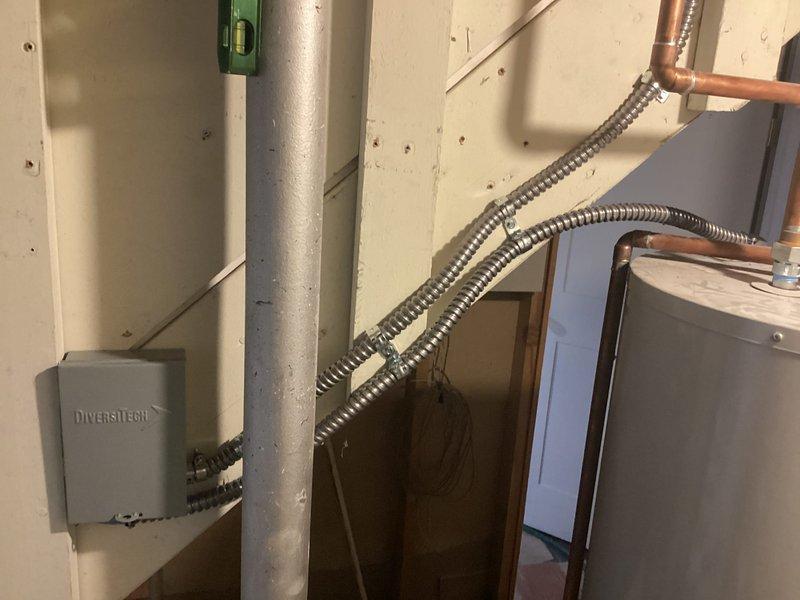 Responded to inspection callback for water heater disconnect installation. Installed electrical disconnect switch with proper conduit and wiring per code requirements on previously installed water heater. Mounted Diversitech disconnect box on utility room wall with metallic flexible conduit connections to water heater. Documented installation with photographs showing completed disconnect installation and uploaded images for inspector approval.
