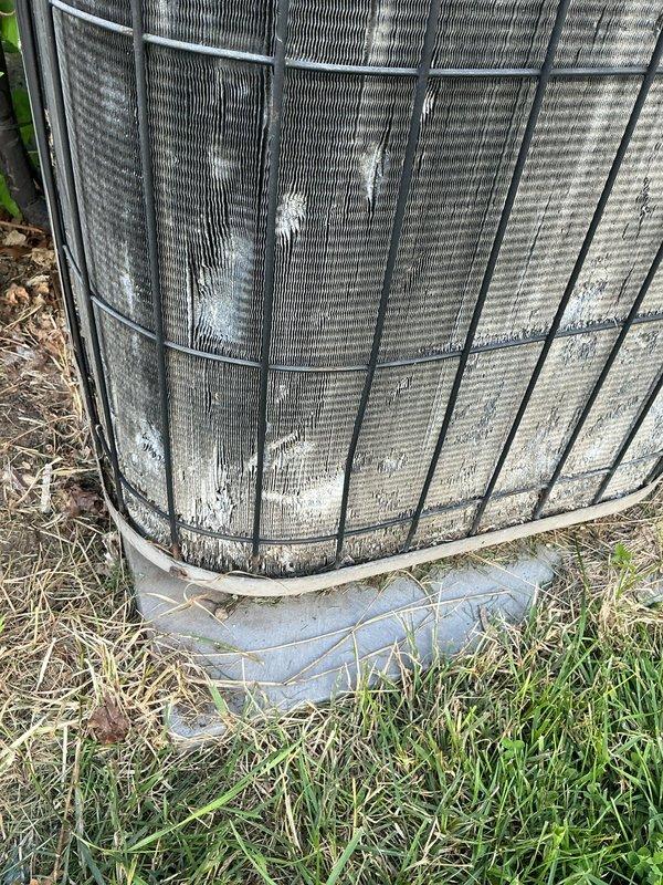 Responded to no cooling complaint with indoor temperature at 78°F despite thermostat set to 69°F. Upon arrival, inspected outdoor condensing unit and found heavily soiled condenser coils with significant dirt, dust, and debris accumulation restricting airflow through the aluminum fins. Wire guard showed overgrown vegetation and organic material around unit perimeter, contributing to reduced system efficiency. Documented condition of outdoor unit with photos showing weathering, mineral deposits, and uneven dirt buildup across coil surfaces. Unit displayed signs of neglected maintenance with unkempt surrounding area affecting performance. Recommended professional coil cleaning and vegetation clearance to restore proper airflow and cooling capacity.