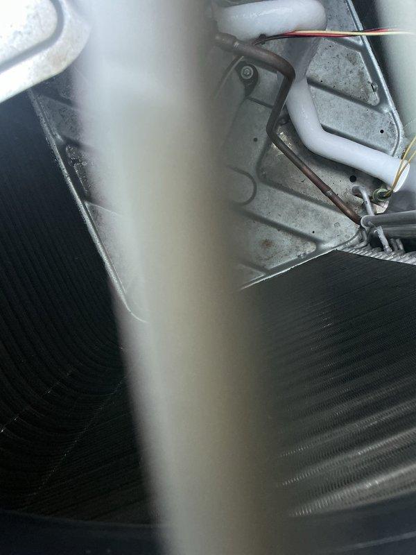 Performed inspection of outdoor condensing unit and indoor evaporator coil assembly. Examined copper refrigerant line connections, condensate drain system with float mechanism, and coil fin condition. Verified proper mounting and secure fastening of all components, with equipment showing normal operational wear and all mechanical elements properly installed and functional.