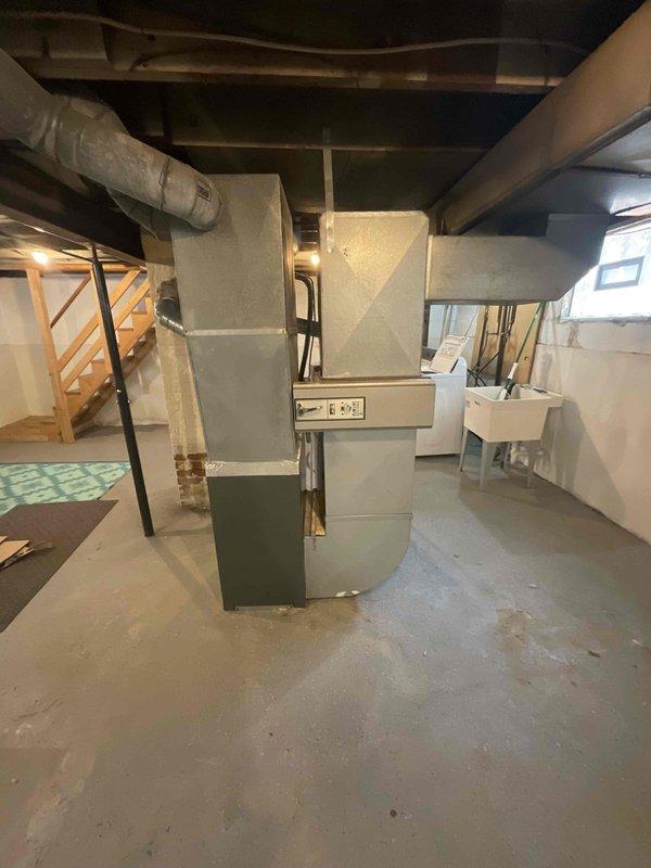 Conducted full system estimate for 16-year-old air conditioning unit located in unfinished basement area. Evaluated existing HVAC equipment, ductwork configuration, and electrical service panel to provide replacement recommendations for system nearing end of service life. Documented current installation with photographs for proposal preparation, noting standard basement setup with exposed joists, concrete flooring, and central furnace/AC configuration with overhead duct distribution.