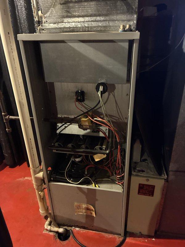 Conducted on-site assessment for complete air conditioning system replacement. Evaluated existing 15-year-old outdoor condenser unit showing significant age-related wear, including weathered metal grille with substantial dirt accumulation and environmental debris. Documented current system configuration with outdoor unit positioned on concrete pad against house foundation, noting electrical disconnect box and conduit connections. Inspected indoor furnace unit and air handler components to determine compatibility requirements for new AC system installation. Photographed existing equipment conditions to support replacement quote preparation for expedited installation scheduling.