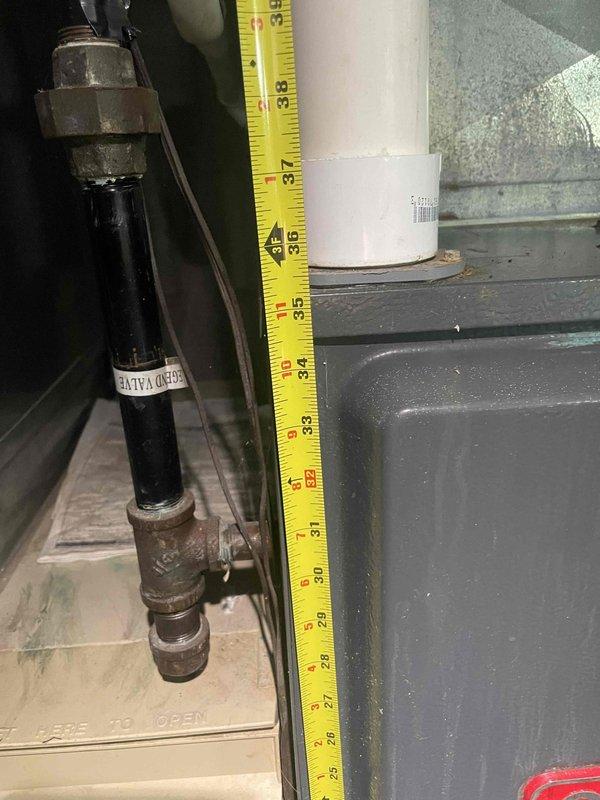 Provided estimate for air conditioning system replacement in basement location. Current unit is non-operational with unknown age. Performed measurements of existing equipment clearances and documented spatial requirements for new installation, including vertical clearances around metal housing and ductwork connections.