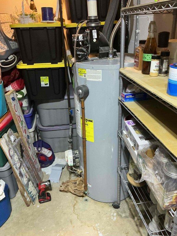 Responded to service call for water heater leak in 29-year-old residence. Upon arrival, inspected gray tanked water heater unit located in basement utility area and identified active leak that had been present for approximately 5 days. Conducted thorough visual inspection of tank, connections, pressure relief valve, and supply lines to determine source of water intrusion. Documented existing conditions with photographs showing water heater installation, surrounding plumbing connections, and evidence of moisture damage on concrete floor. Given the age of the unit and nature of the leak, provided assessment and recommendations for repair or replacement options to address the issue and prevent further water damage to the property.