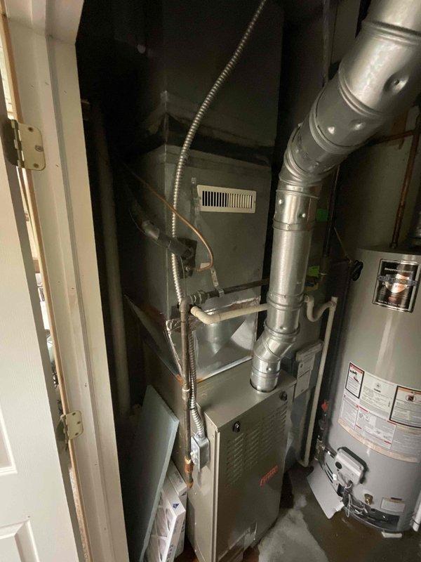 Responded to service call for non-operational air conditioning system. Upon inspection, confirmed complete system failure of 25-year-old AC unit that had exceeded its expected service life. Evaluated existing Trane HVAC equipment located in basement utility closet, including air handler, ductwork configuration, and associated components. Documented current installation setup with air handler positioned adjacent to water heater in confined mechanical space, noting vertical ductwork runs and existing electrical conduit routing. Prepared comprehensive estimate for complete AC system replacement to restore cooling functionality. Recommended full system replacement due to age and obsolescence of existing equipment, emphasizing priority timeline to meet immediate cooling needs.