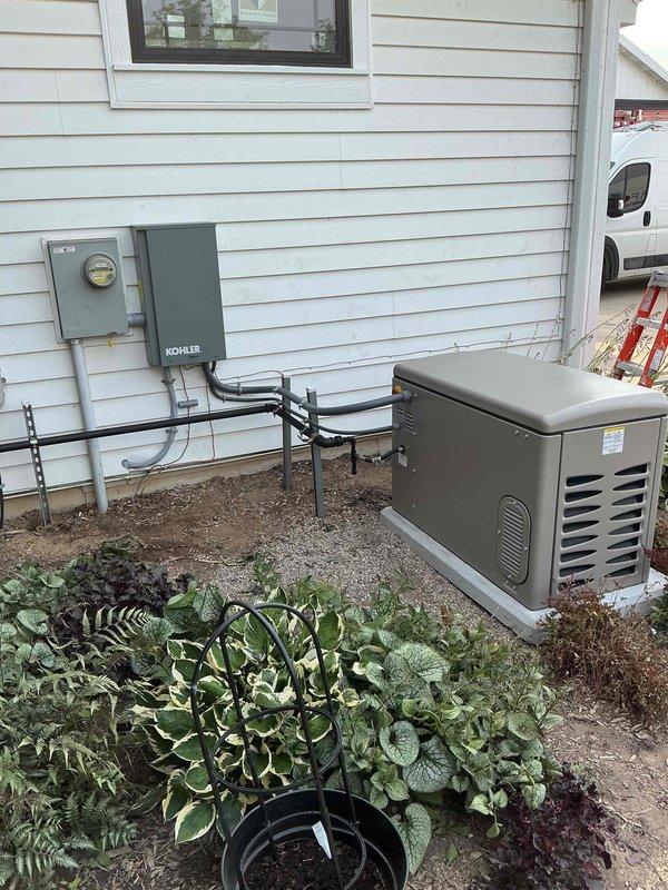 Completed installation of Kohler 20kW residential standby generator (Model 20RCA) with associated transfer switch and electrical connections. Coordinated utility disconnect and reconnect service with power company for safe installation. Generator mounted on prepared gravel base pad adjacent to home exterior, with proper clearances maintained from structure and landscaping. Installed gray Kohler-branded automatic transfer switch on exterior wall with conduit runs connecting to existing electrical meter, generator unit, and home electrical system. All electrical connections completed per manufacturer specifications and local code requirements. Permit obtained and final inspection confirmed successful. Unit tested and operational, ready to provide automatic backup power during utility outages.