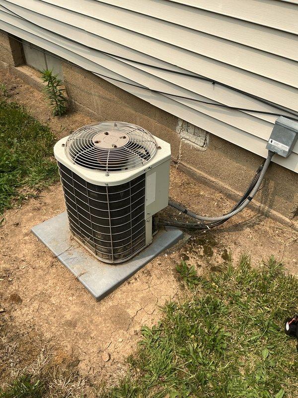 # HVAC Service Completed

Responded to no-cooling complaint on 10+ year-old residential air conditioning system. Unit was not reaching set point temperature of 72°F, remaining at 77°F throughout the house. Customer reported temporary resolution after power cycling the unit and noted similar issue two years prior that required capacitor replacement.

Upon arrival, performed visual inspection of outdoor condenser unit. Unit is installed on concrete pad with standard refrigerant line set and electrical disconnect present. Examined condenser coil condition and observed typical wear consistent with age of equipment. Documented equipment condition with photos showing condenser unit exterior, coil fins, and cabinet components.

Conducted diagnostic evaluation to determine root cause of cooling deficiency. Given the system's age (10+ years), history of capacitor failure, and intermittent nature of the problem, performed electrical component testing including capacitor values, contactor operati