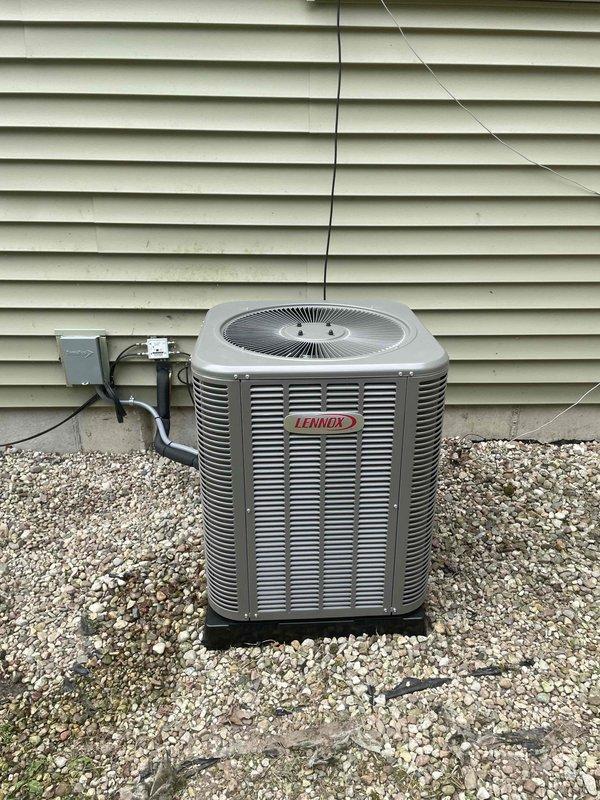 Completed installation of 2-ton Lennox air conditioning condensing unit with matching evaporator coil at rear of residence. Unit positioned on composite pad over gravel bed with proper clearance from structure, electrical disconnect installed and wired per code, refrigerant lines connected and system commissioned. All required permits obtained, system tested and left operational with proper airflow and temperatures.