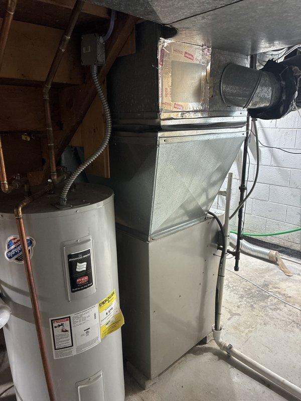 Conducted comprehensive assessment of existing 22-year-old furnace and air conditioning system for full replacement estimate at residential property. Inspected basement-installed HVAC equipment including gray metal furnace/air handler unit with associated ductwork and reflective insulation, evaluated electrical panel and circuit breaker configuration supporting system operation, and documented current equipment condition through photographic documentation. Both heating and cooling units are original to the home and have reached end of expected service life, requiring complete system replacement recommendations to be provided to homeowner.