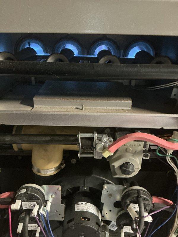 Completed comprehensive AC tune-up and system checkup on Envox HVAC unit per customer's air care maintenance plan. Performed electrical diagnostics using clamp meter to verify proper amperage draw on blower motor and system components. Inspected gas furnace burner operation, confirming all four burners ignited properly with clean blue flames. Verified all electrical connections, motor assemblies, and Honeywell control components functioning within normal parameters. System tested and confirmed operating properly with no issues found.