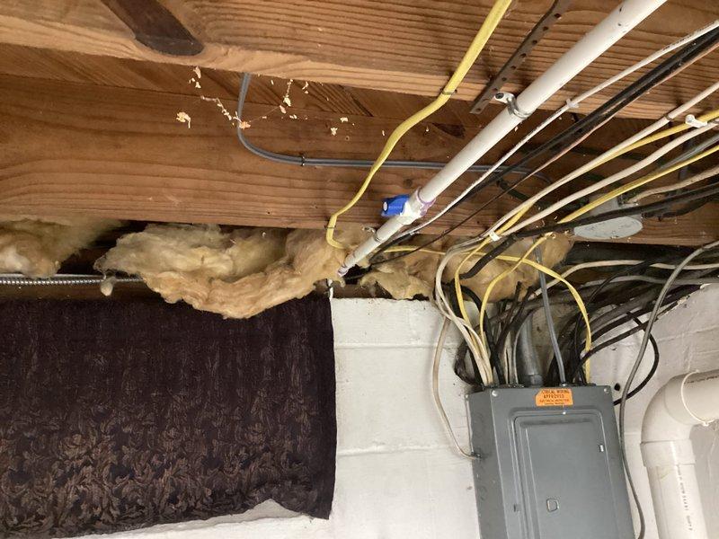 Completed installation of 2-ton air conditioning system with evaporator coil at rear location. Obtained mechanical and electrical permits prior to installation and established new dedicated electrical circuit to support the system. During installation, identified code violations including improper wire installation methods where conductors were stapled to floor joists rather than routed through bored holes, and non-compliant use of tandem breaker in electrical panel not rated for such configuration.
