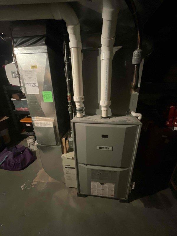 Conducted comprehensive assessment of existing HVAC system for replacement estimate at owner-occupied residence. Evaluated 25-year-old Ameristar furnace and air conditioning system currently installed in basement utility area. Documented existing equipment configuration including furnace unit with dual PVC venting system and associated air handler components. Photographed current installation showing proper venting arrangement and equipment placement for replacement planning purposes. Assessed access points and installation conditions, noting property located on easement with deck-level access and lattice-enclosed crawl space. Provided replacement recommendations for complete HVAC system upgrade due to age of existing equipment, with customer requesting expedited installation timeline.
