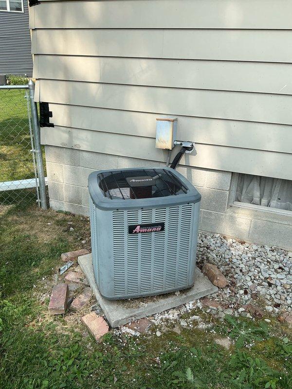 Responded to service call for 10-year-old Amana central air conditioning system experiencing inadequate cooling on main floor during extreme temperatures, while basement maintained proper cooling. Performed comprehensive system evaluation of outdoor condensing unit and indoor air handler/furnace assembly. Inspected outdoor unit positioned on concrete pad, noting weathered cabinet condition consistent with age but operational components. Evaluated refrigerant line routing and electrical disconnect box. Conducted indoor equipment assessment of Amana furnace and air handler unit in basement mechanical room, examining ductwork configuration including white PVC condensate drainage system. Assessed airflow distribution patterns between basement and main floor zones to identify cooling capacity limitations. Provided maintenance recommendations to optimize system performance during peak cooling demands and established preventative maintenance schedule for ongoing system efficiency.