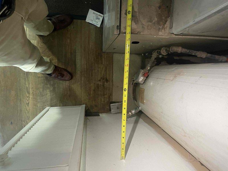 Conducted site assessment for replacement estimate of 30+ year old non-operational ground-level AC unit located behind building and potential natural gas furnace replacement. Documented existing equipment dimensions and installation space measurements in utility area to determine specifications for new HVAC system installation.