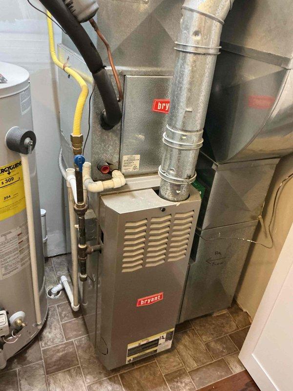 Performed comprehensive diagnostic evaluation on approximately 20-year-old Bryant residential cooling system for new homeowner experiencing unspecified operational concerns. Inspected outdoor condenser unit positioned against building exterior, noting unit condition and surrounding clearances adequate despite age. Verified electrical connections at outdoor unit including conduit routing and power supply integrity. Assessed indoor furnace and air handler components in mechanical room, examining ductwork connections, plenum assembly, and airflow pathways. System demonstrated continued cooling capacity during evaluation, though age-related wear consistent with two-decade operation timeline was evident throughout equipment inspection.