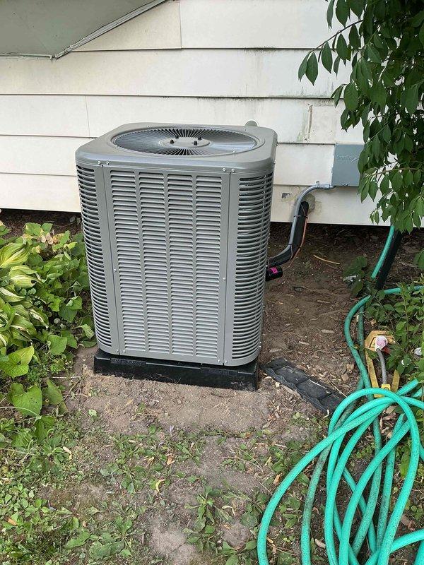 Completed installation of 2-ton air conditioning condenser unit and evaporator coil system. Mounted outdoor condenser on pad against exterior wall with refrigerant line set routed through building penetration. Connected new evaporator coil to existing furnace in basement, integrated with ductwork system using flexible and rigid connections. Installed all necessary refrigerant piping, electrical connections, and condensate drainage. Verified proper system operation, refrigerant charge, and airflow throughout completed installation.