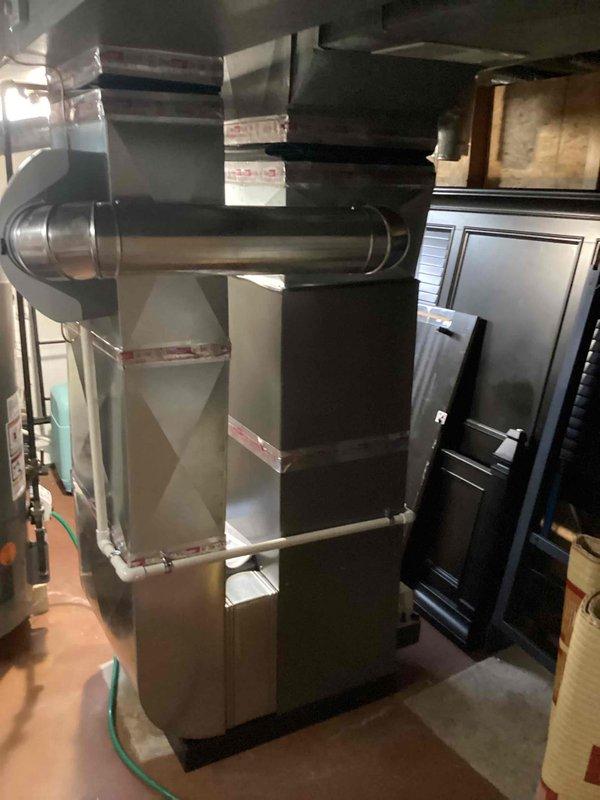 Completed full HVAC system installation including 70,000 BTU furnace with humidifier and 2-ton air conditioning unit with evaporator coil in residential basement location. Installed all necessary ductwork connections, PVC condensate and vent piping, refrigerant line set to rear-mounted outdoor condenser unit, and reconnected existing electrical service. Mechanical permit obtained and all equipment positioned on protective floor covering with proper clearances maintained for service access and code compliance.