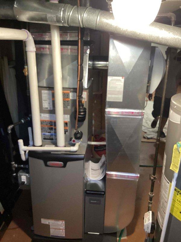 Completed full HVAC system installation including 70,000 BTU furnace with humidifier and 2-ton air conditioning unit with evaporator coil in residential basement location. Installed all necessary ductwork connections, PVC condensate and vent piping, refrigerant line set to rear-mounted outdoor condenser unit, and reconnected existing electrical service. Mechanical permit obtained and all equipment positioned on protective floor covering with proper clearances maintained for service access and code compliance.