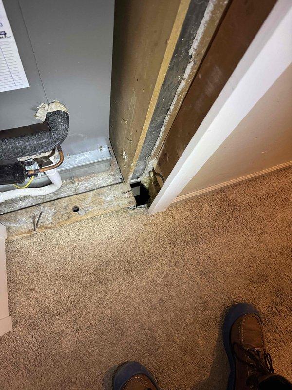 Responded to service call for reported hole in bottom of furnace unit located in basement. Upon arrival, performed visual inspection of 2-year-old furnace system and surrounding area. Investigation revealed significant structural deterioration in wooden framing members adjacent to HVAC equipment, with evidence of moisture damage, wood decay, and greenish-gray discoloration consistent with mold growth. Documented extensive damage to wall framing where structural members meet, showing gaps, cracks, and compromised wood integrity. Photographed flexible ductwork connections and cabinet installation to document current system configuration and proximity to damaged structural elements. Advised customer that observed deterioration poses potential risk to HVAC system integrity and recommended immediate consultation with qualified contractor to address structural damage and moisture intrusion source before proceeding with furnace repairs. Work performed under applicable parts and labor warranty