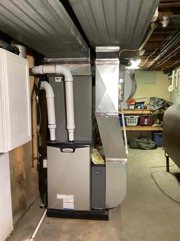 Completed full HVAC system installation including a 90,000 BTU furnace with humidifier and 3.5-ton air conditioning unit with rear discharge configuration. Installed new furnace in basement utility area with PVC venting routed through ceiling joists, connected metal ductwork and plenum assembly, and positioned Lennox condenser unit on concrete pad against exterior wall with proper refrigerant line connections. All mechanical permits were obtained prior to installation, system was tested and commissioned, and existing electrical connections were reconnected to ensure proper operation of both heating and cooling components.