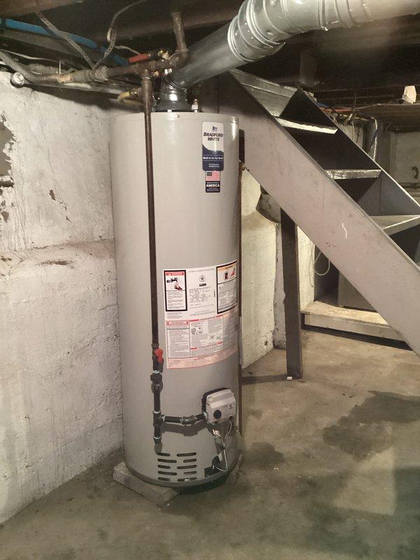 Installed Bradford White tanked water heater model RG240T6N in basement location on concrete floor against masonry wall. Connected water supply lines and configured piping to top of unit, ensuring proper integration with existing plumbing infrastructure including exposed joists and ductwork systems. Permit was previously requested and all required documentation was completed for financing approval.