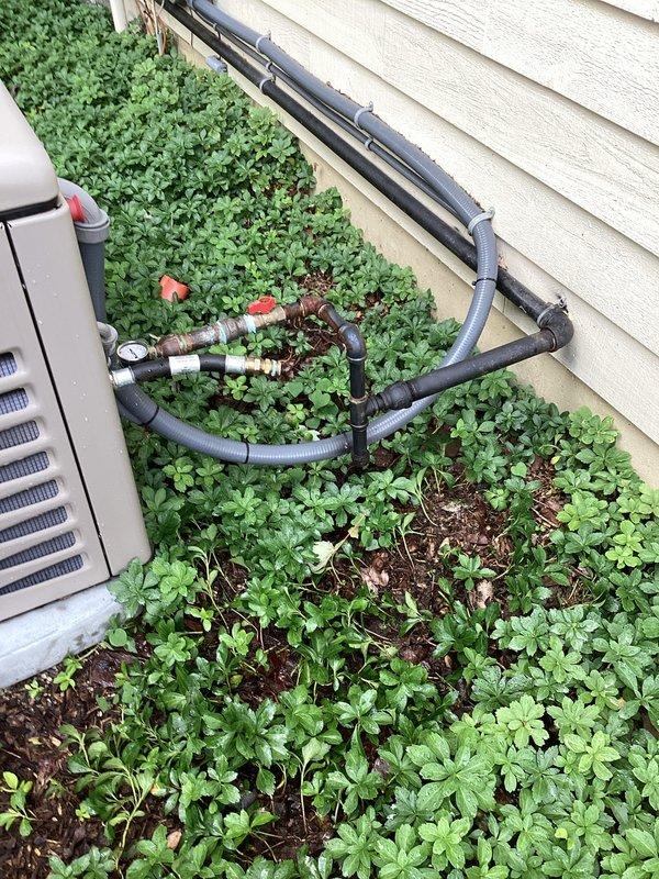 Performed pressure test on generator installation piping system located at exterior HVAC area. Verified all connections, fittings, and valves on black plastic piping configuration with pressure gauge readings within acceptable parameters, confirming system integrity and proper installation of refrigerant lines secured to building exterior.
