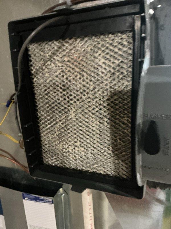 Completed annual cooling maintenance on residential Luxaire HVAC system. Inspected furnace unit, air handler, and associated ductwork for proper operation and component condition. Accessed filter compartment and documented mesh filter condition showing significant dust and debris accumulation throughout the filter media. Photographed system configuration including condensate drain lines, flexible vent connections, and electrical wiring for service records. All major components visually inspected and system operational status verified.
