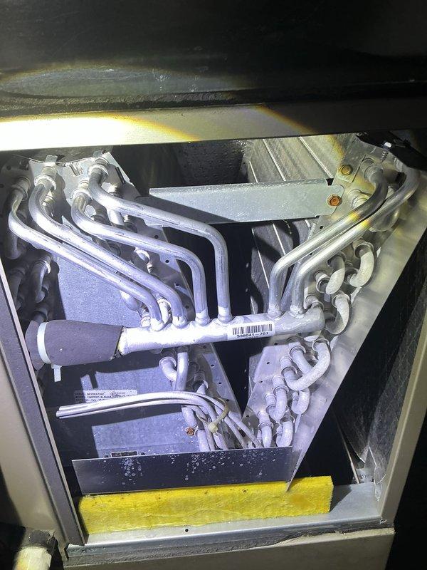 Performed annual cooling tune-up on residential split system air conditioning unit. Inspected indoor evaporator coil assembly located in attic space and outdoor condensing unit with cylindrical fan housing. Completed comprehensive system evaluation including coil condition assessment, refrigerant level verification, electrical connections inspection, and airflow testing. Both indoor and outdoor components showed normal operating condition with minor dust accumulation noted on coil surfaces. Recommended vegetation clearance around outdoor unit to maintain proper airflow and equipment efficiency.
