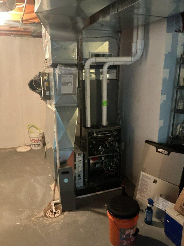 Completed comprehensive 5-year ComfortGuard Maintenance visit on residential HVAC system located in basement utility area. Performed thorough inspection of furnace unit and air handler, with access panel opened to examine internal components including burners and mechanical assemblies. Verified proper operation of all mechanical parts and connections. Inspected air filtration system with honeycomb mesh filter installed in black metal frame housing, confirming adequate airflow and filter condition. Examined ductwork configuration including flexible ducting and metal supply runs. All equipment found operating within normal parameters with no immediate service needs identified.