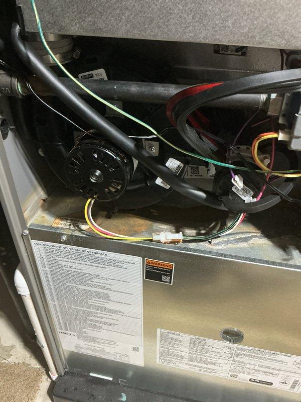 Responded to warranty call for water leaking from 3-year-old furnace unit. Upon inspection, accessed interior compartments and identified moisture issue related to drainage system. Observed condensate drain line and associated components, noting rust-colored staining on metal shelf area indicating previous water presence. Verified all electrical connections, control board functionality, and blower assembly operation. Cleared condensate drain obstruction, tested system operation to confirm proper drainage flow, and ensured no further leakage present. Unit restored to normal operating condition under parts and labor warranty coverage.