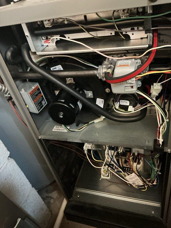 # HVAC System Maintenance Completed

Performed comprehensive ComfortGuard maintenance inspection on residential HVAC unit. Accessed internal components by removing service panels to conduct thorough system evaluation. 

Inspected blower motor assembly, air handling components, and curved black ducting for proper operation and wear. Verified all electrical connections including red, white, green, and yellow wire harnesses were secure and properly terminated. Examined gray metal mounting plates and component supports for stability.

Replaced air filter and evaporator pad as specified for this maintenance interval. Checked manufacturer specification labels and safety warnings for compliance and legibility.

Evaluated blower motor housing, fan assembly, and associated mechanical components for normal wear patterns. Inspected blue metallic air handling components and white motor assembly with attached red tubing for proper function. Verified all warning labels remained visible and intact th