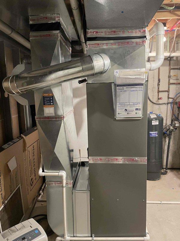Completed full HVAC system installation including a 90,000 BTU high-efficiency furnace with integrated humidifier, 3-ton air conditioning unit positioned on left side of property, and tankless water heater. All mechanical equipment installed in basement utility area with proper ductwork connections, refrigerant lines run to exterior condensing unit mounted on concrete pad, and necessary electrical disconnects installed per code requirements.