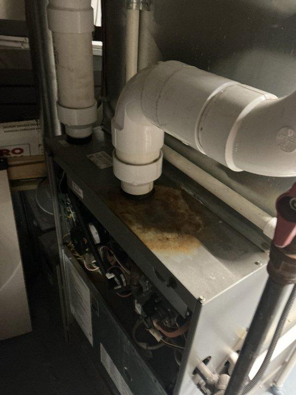 Responded to service call for water leakage from furnace occurring when air conditioning system was in operation. Upon arrival, inspected 11-year-old HVAC system located in basement. Found evidence of significant water damage and rust staining on top surface of furnace cabinet, indicating ongoing condensate drainage issue. Removed access panel and performed thorough internal inspection of furnace components, blower assembly, and condensate management system. Identified condensate drain line obstruction causing water backup and overflow onto furnace cabinet during AC operation. Cleared blockage from drain line and verified proper drainage flow. Inspected evaporator coil, drain pan, and associated plumbing connections for additional issues. Tested system operation in cooling mode to confirm water is now draining properly through condensate lines without leakage. System operating as designed with no further water discharge onto equipment.