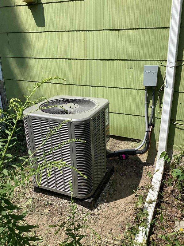Completed installation of 2-ton air conditioning system with matching evaporator coil at residential property. Positioned outdoor condenser unit on concrete pad against exterior wall with proper clearances, installed new electrical disconnect box and dedicated circuit per code requirements, and ran insulated refrigerant lines into building connecting to indoor coil. System was pressure tested, evacuated, charged to manufacturer specifications, and tested for proper operation with all electrical connections secured and condensate drainage confirmed functional.