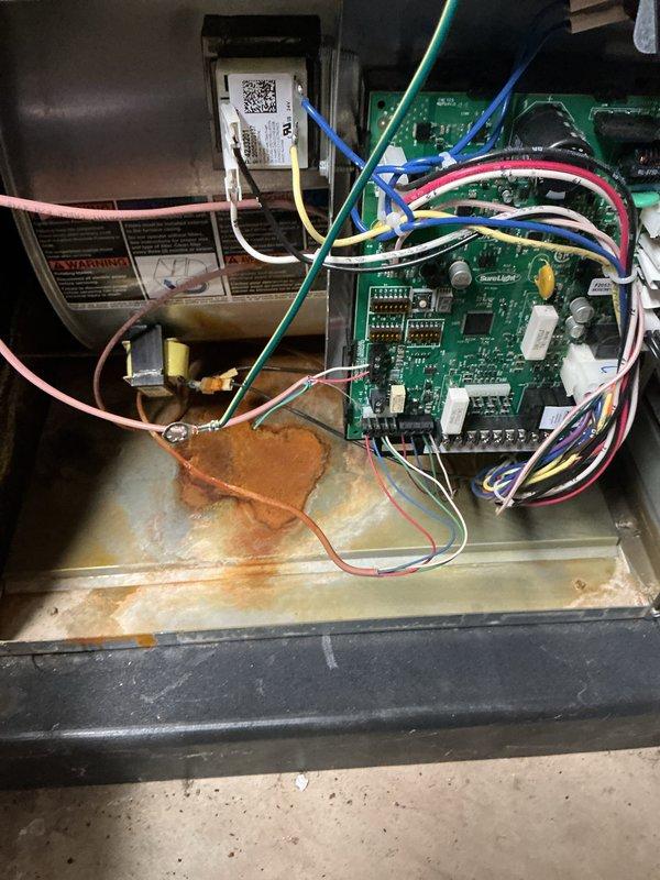 Completed comprehensive furnace tune-up and safety inspection on 5-year-old unit located in basement. Inspection included thorough evaluation of heating system, humidifier, Lennox digital thermostat (confirmed operational at 71°F with heat set to 77°F), and hot water tank. Notable findings included rust-colored corrosion on furnace base pan indicating previous moisture intrusion or condensate drainage issues; control board and electrical connections inspected and found functioning properly with all wire terminations secure.
