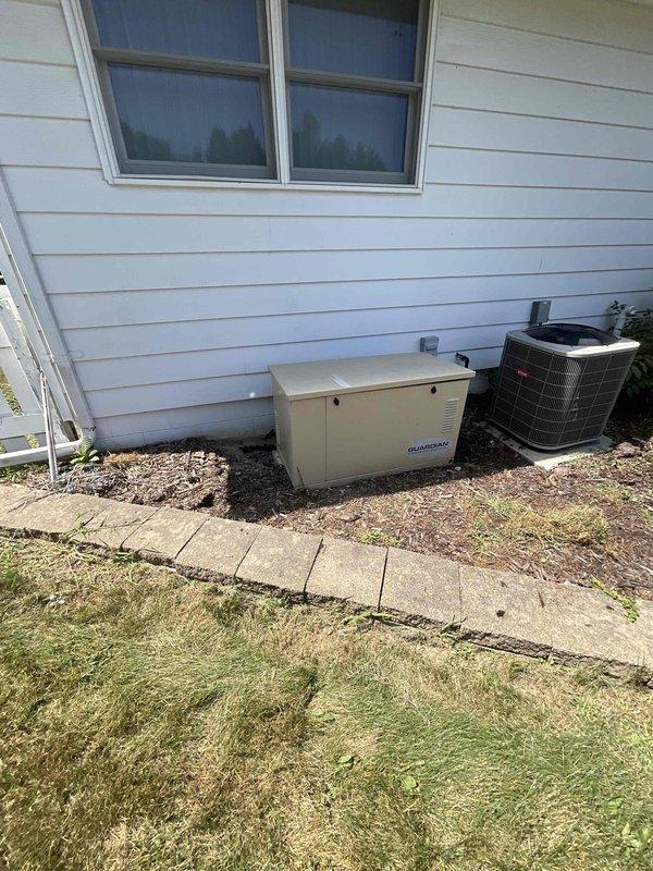 Conducted site assessment of existing Generac whole house standby generator experiencing oil leak requiring replacement. Evaluated current installation location on exterior gravel pad adjacent to air conditioning unit, inspected transfer switch and electrical connections in basement utility room, documented equipment condition and configuration. Photographed generator unit, outdoor installation setup, interior electrical panel, and associated wiring to prepare comprehensive replacement estimate for new whole house generator system.