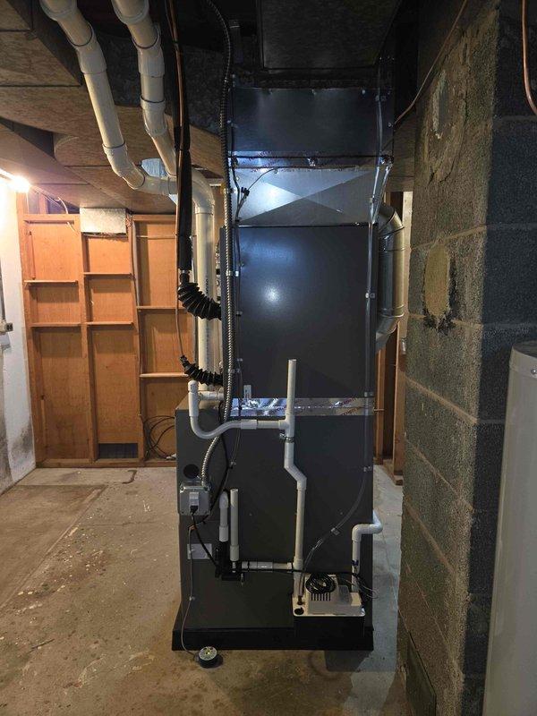 Completed full HVAC system installation including a 90,000 BTU furnace with humidifier and 3-ton air conditioning unit with rear discharge configuration. Installed new equipment in basement mechanical room on platform base with proper condensate drainage routed through exterior wall via PVC piping. All ductwork connections completed, electrical reconnected, and venting properly installed per manufacturer specifications.
