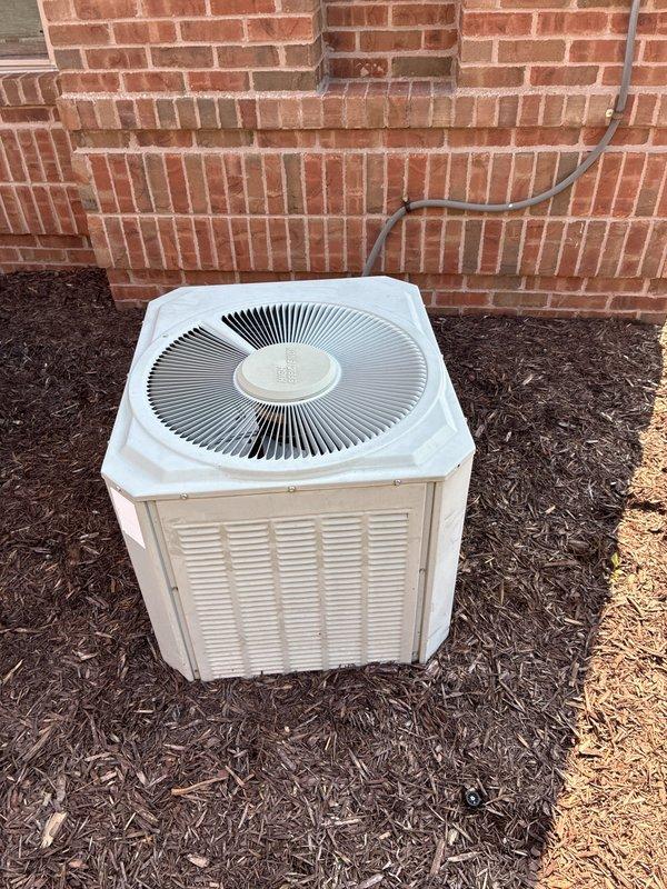 Provided estimate for replacement of 22+ year old non-operational commercial ground-level air conditioning unit located at rear of building. Existing system positioned on mulch bed adjacent to brick wall with refrigerant lines and electrical conduit running to building connection point. Assessed site conditions, documented equipment specifications, and prepared replacement proposal for new AC system with natural gas furnace compatibility.