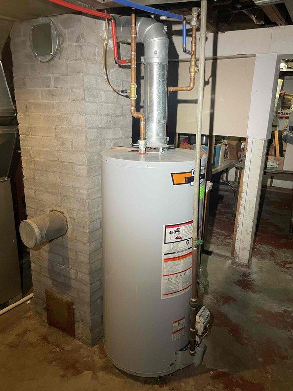 Provided estimate for replacement of non-functioning standard natural draft water heater in residential basement. Assessed existing white cylindrical tank unit with metallic vent pipe, copper and PEX plumbing connections, and natural draft venting configuration. Customer requested standard tank replacement rather than tankless conversion, with preference for call-ahead communication only.