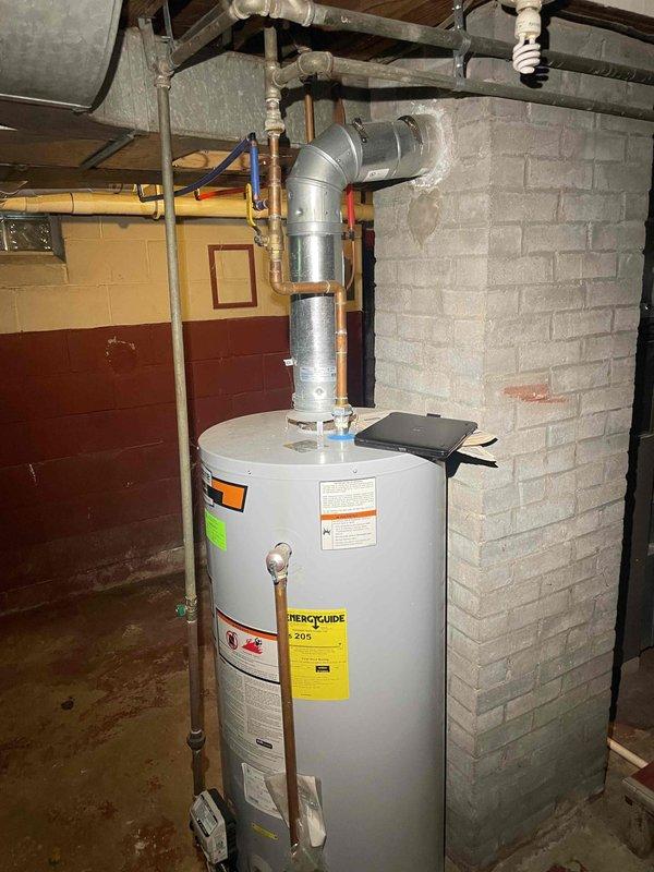 Provided estimate for replacement of non-functioning standard natural draft water heater in residential basement. Assessed existing white cylindrical tank unit with metallic vent pipe, copper and PEX plumbing connections, and natural draft venting configuration. Customer requested standard tank replacement rather than tankless conversion, with preference for call-ahead communication only.