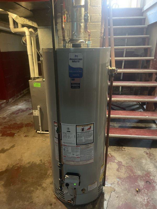 Successfully installed a new 50-gallon Bradford White tanked water heater in the basement utility area. Completed all necessary plumbing connections including copper supply lines, discharge piping, and PVC venting routed through the exterior wall. Installation performed in accordance with manufacturer specifications and local code requirements, with permits obtained prior to work commencement.