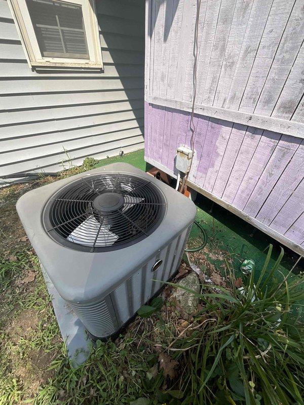 Provided estimate for air conditioning system replacement at residential property. Current 5-year-old outdoor condenser unit, located on concrete pad in side yard between buildings, is non-operational and requires full replacement. Indoor air handling equipment is positioned in basement and will be included in replacement scope.