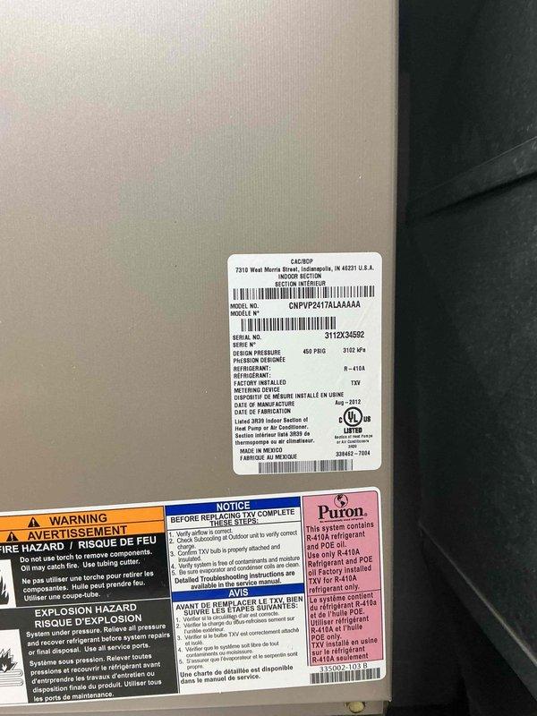 Responded to no-cooling call on Carrier central air conditioning system. Upon arrival, performed diagnostic inspection of HVAC system including furnace and air handler assembly. Documented equipment specifications and current system condition with model number CNPVP2417ALA4AAA, serial number 3112X34592, utilizing Puron refrigerant. System evaluated and photographed for service records showing proper installation configuration with white PVC condensate drainage, ductwork connections, and electrical components in operational condition.