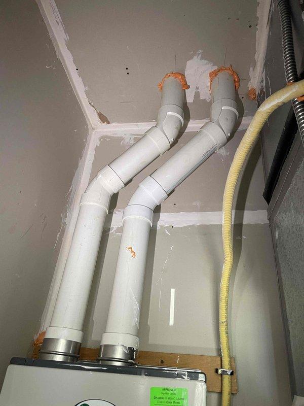 Completed on-site evaluation for replacement of existing gas tank water heater. Assessed current working unit and existing plumbing infrastructure, including wall-mounted equipment with complex PEX and copper supply line configurations, shut-off valves, and pressure relief components. Documented installation specifications for gas-fired water heater replacement, noting natural draft venting requirements and existing mechanical room layout with color-coded hot and cold water distribution systems.