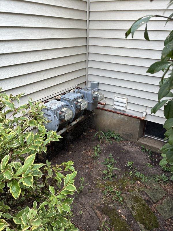 Conducted comprehensive site evaluation for whole home generator installation at residential property with shared driveway access. Assessed existing electrical service configuration consisting of three digital utility meters with associated disconnect panels and conduit runs on exterior wall. Evaluated current outdoor mechanical equipment placement and utility corridor to determine optimal generator positioning, load requirements, and integration with multi-meter electrical system. Documented site conditions including available mounting surfaces, clearance requirements, fuel supply routing options, and necessary electrical connections to support automatic transfer switch installation and generator tie-in to existing service panels.