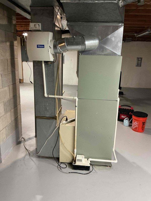 Responded to water leak complaint at basement HVAC system. Upon arrival, found approximately two gallons of water pooled on basement floor near 33-year-old York evaporator coil cabinet with visible moisture on surrounding components. Inspected evaporator coil cabinet, drain pan, and condensate drainage system. Identified clogged condensate drain line as source of overflow. Cleared blockage from drain line, verified proper drainage flow, and cleaned drain pan. Tested system operation to confirm heating and cooling functionality remained intact. Extracted standing water from floor and wiped down dampened areas around cabinet. System restored to normal operation with proper condensate drainage confirmed.