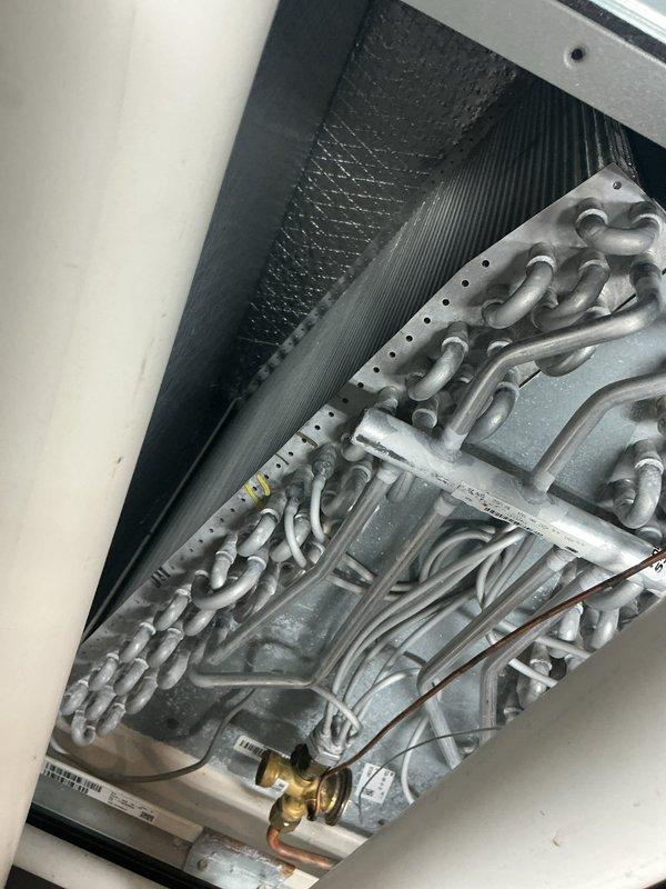 Responded to service call for chemical/chlorine odor emitting from supply vents during air conditioning operation on 4-year-old Lennox system. Performed thorough inspection of evaporator coil assembly and heat exchanger components. Accessed air handler unit and examined A-coil for signs of contamination, biological growth, or refrigerant leak that could produce chemical odors. Inspected condensate drain line and pan for standing water or microbial buildup. Verified refrigerant line connections and brass fittings for proper seal integrity. System confirmed operational with cooling capacity maintained throughout inspection.