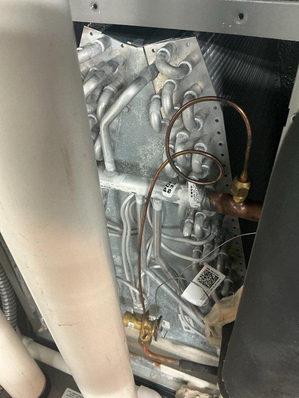 Responded to service call for chemical/chlorine odor emitting from supply vents during air conditioning operation on 4-year-old Lennox system. Performed thorough inspection of evaporator coil assembly and heat exchanger components. Accessed air handler unit and examined A-coil for signs of contamination, biological growth, or refrigerant leak that could produce chemical odors. Inspected condensate drain line and pan for standing water or microbial buildup. Verified refrigerant line connections and brass fittings for proper seal integrity. System confirmed operational with cooling capacity maintained throughout inspection.